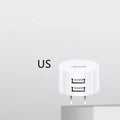 White dual USB phone charger with international plugs for US EU UK regions showing compact 39mm diameter design