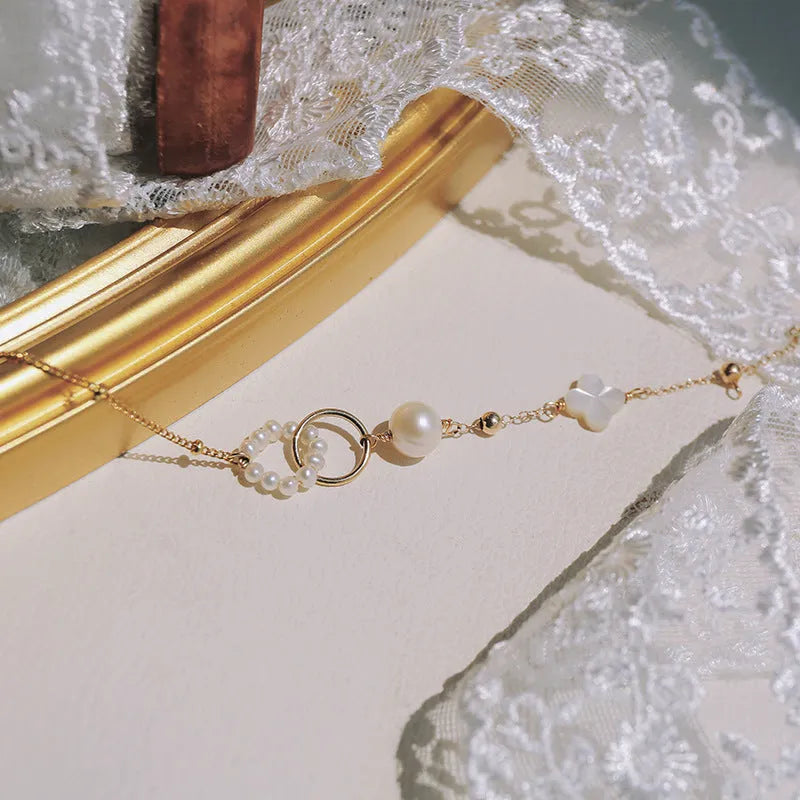 Women's natural freshwater pearl bracelet with gold-plated clasp and floral charm accents on a white background.