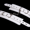 White PU sponge bondage set showing handcuffs, foot cuffs, and a neck scarf laid flat.