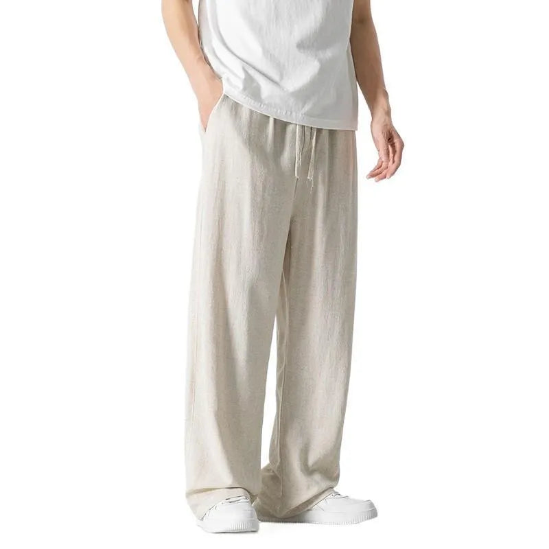Man wearing beige cropped straight-leg bamboo fibre trousers with a drawstring waist on a summer day.