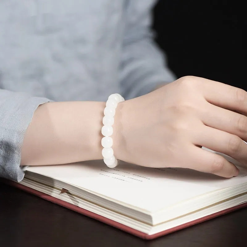 White Hetian jade barrel bead bracelet showing smooth, polished beads on a wrist.