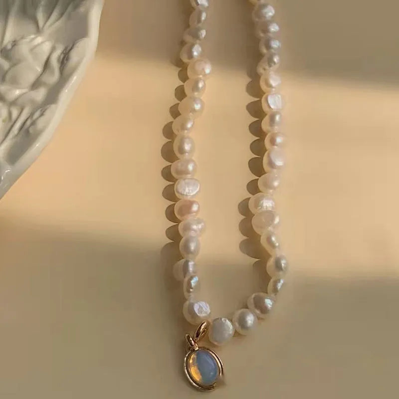 Gold electroplated adjustable vintage pearl necklace with a geometric charm on a black background.