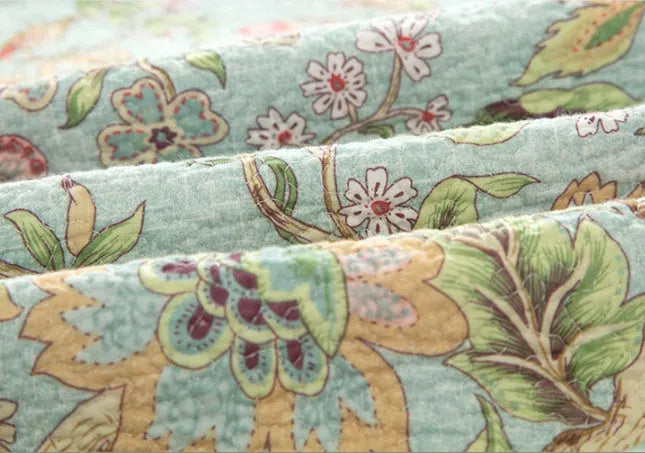 Blue American floral and bird pattern quilted cotton bedspread set on a bed