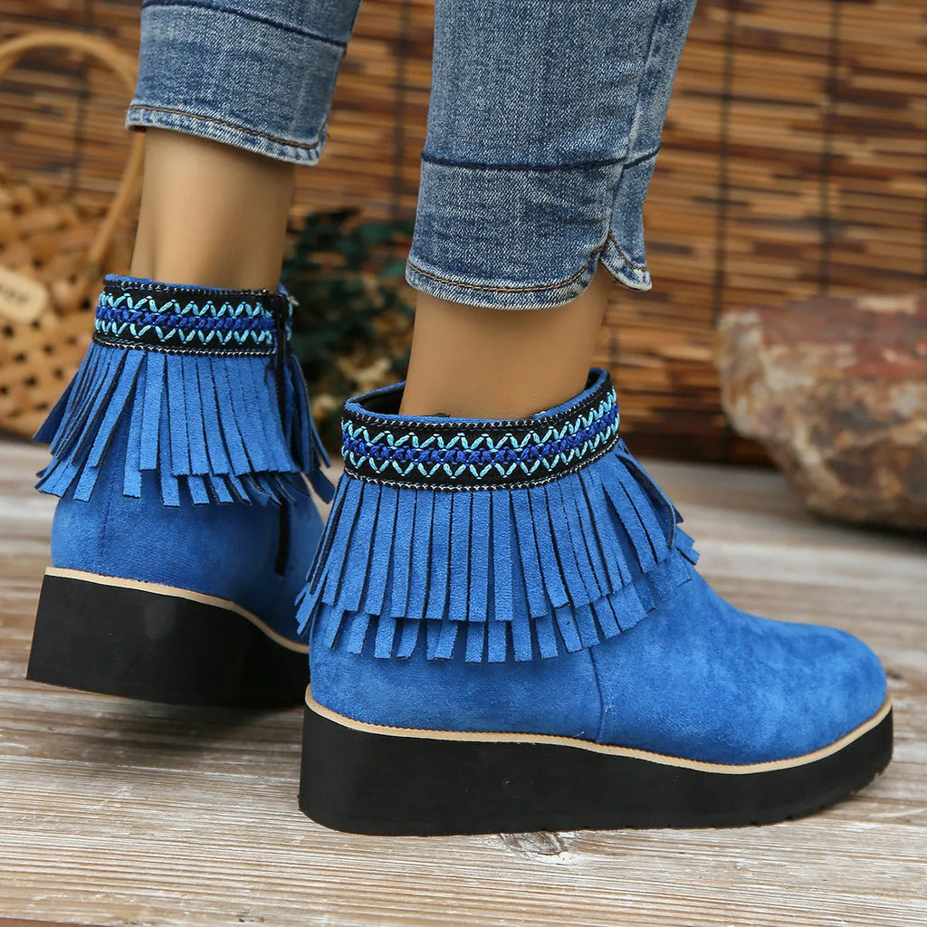 Women's black wedge bootie with suede upper, thick rubber sole, side zipper, and tassel detail.