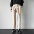 Man wearing loose fit straight leg trousers in apricot colour against a plain background.