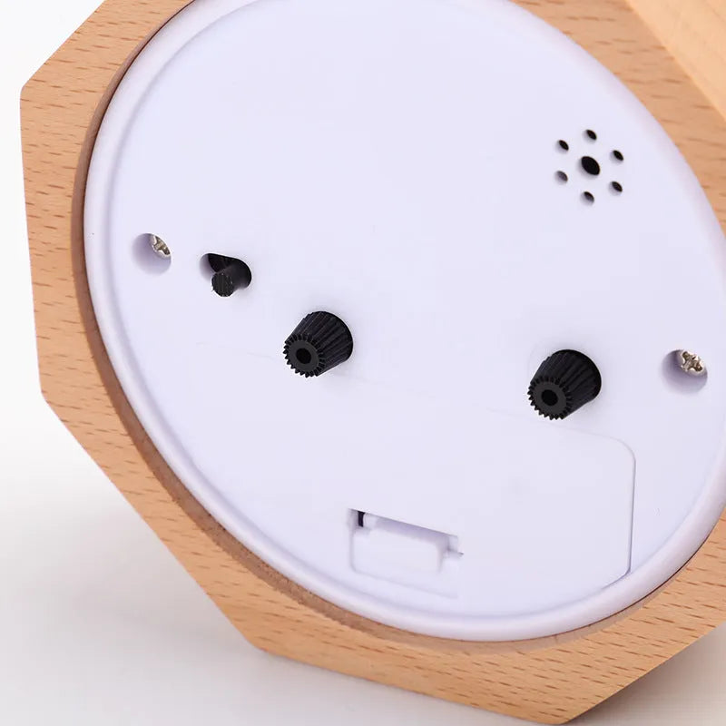 Wooden hexagonal alarm clock with luminous dial and beech finish on a nightstand