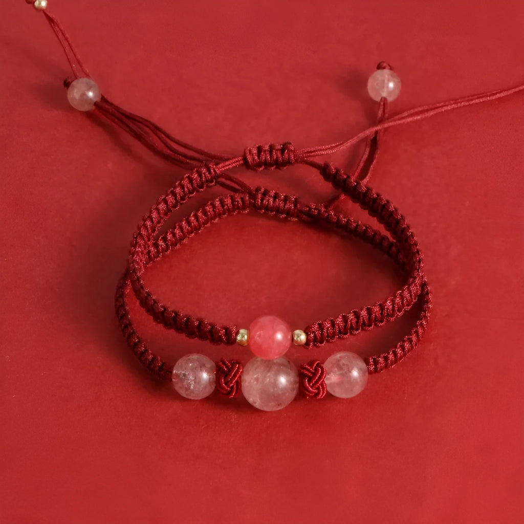 A woven red rope bracelet with a natural strawberry quartz bead and an alloy clasp.