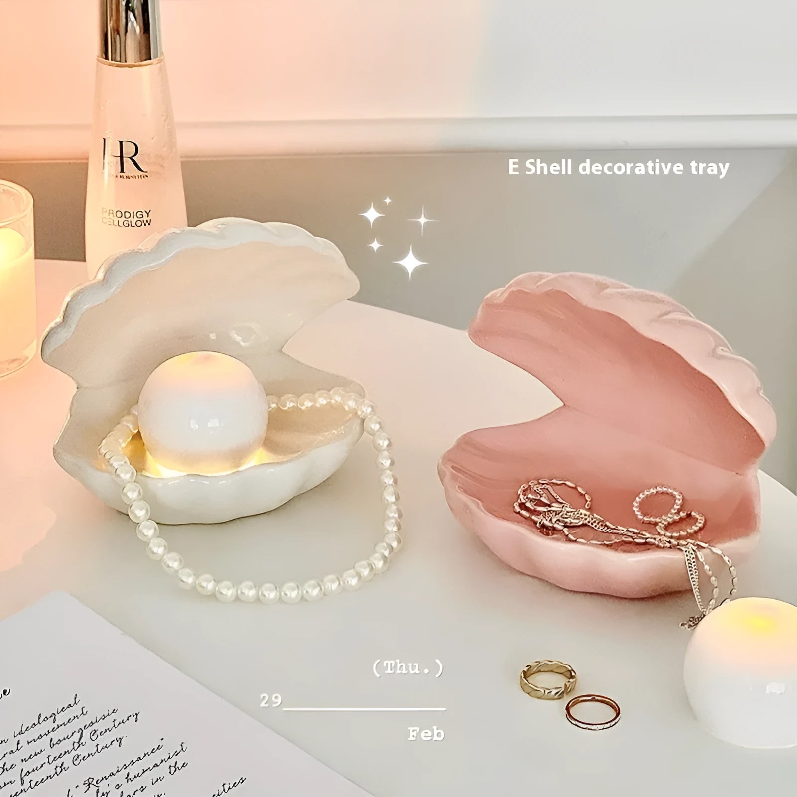 White and pink porcelain shell-shaped tray with integrated yellow LED night light on a wooden table.