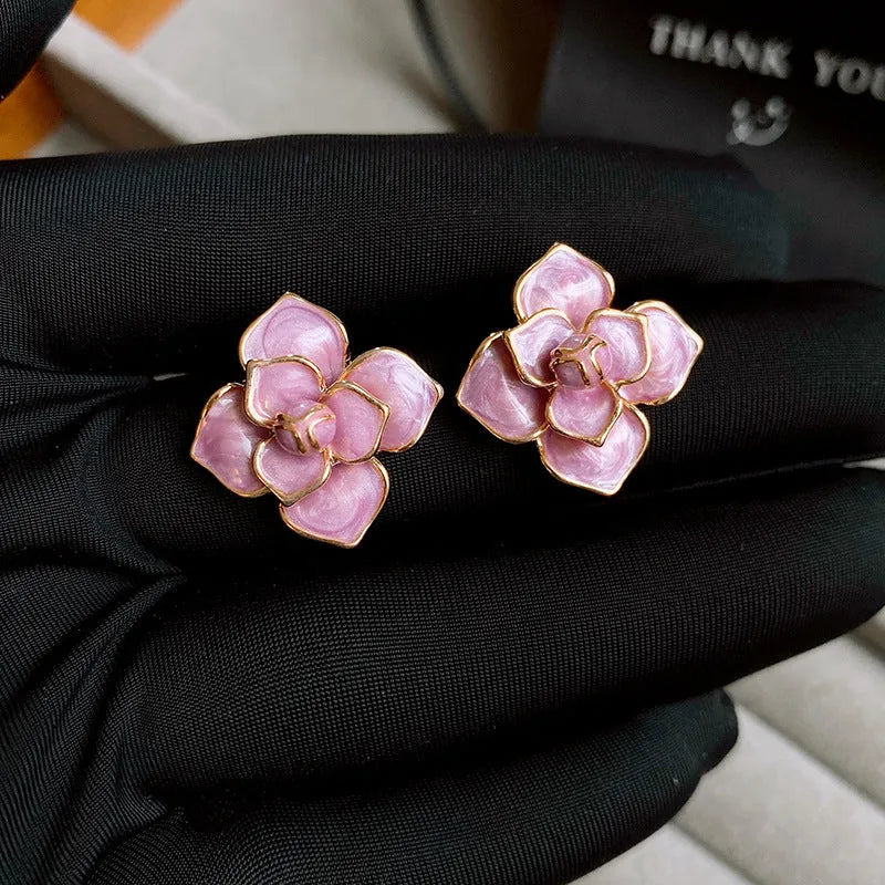 A pair of gold-plated purple oil-spot glaze flower stud earrings made from copper, showing detailed floral texture.
