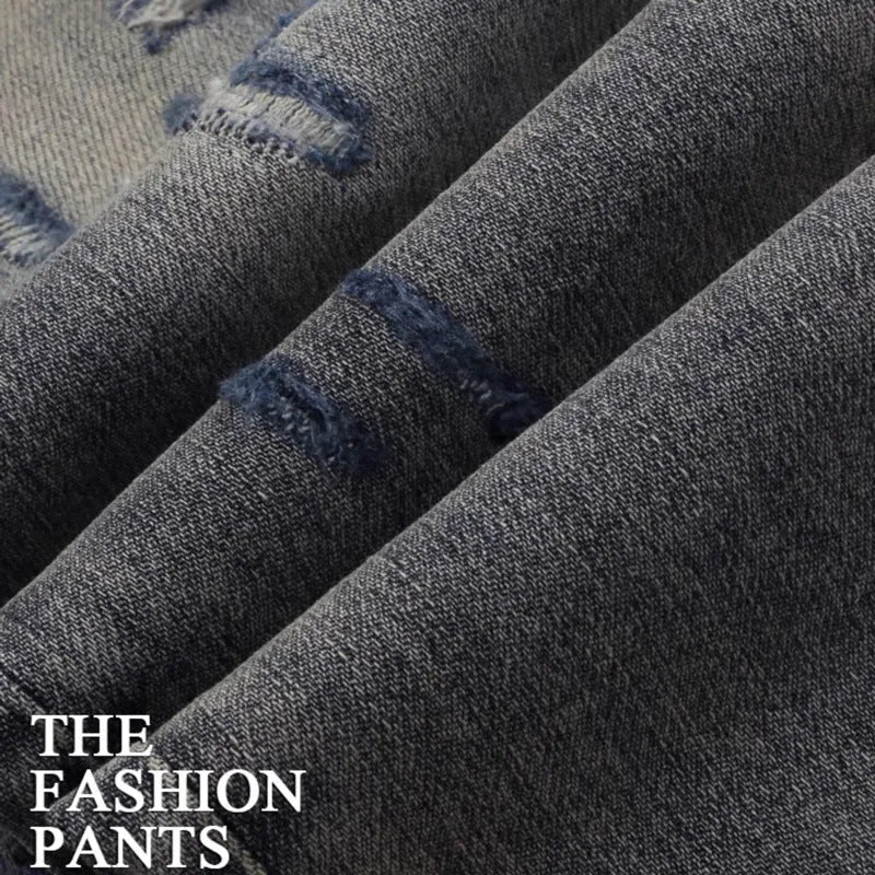 Man wearing slim-fit light blue jeans with distressed knee patches and embroidered back pocket detail.