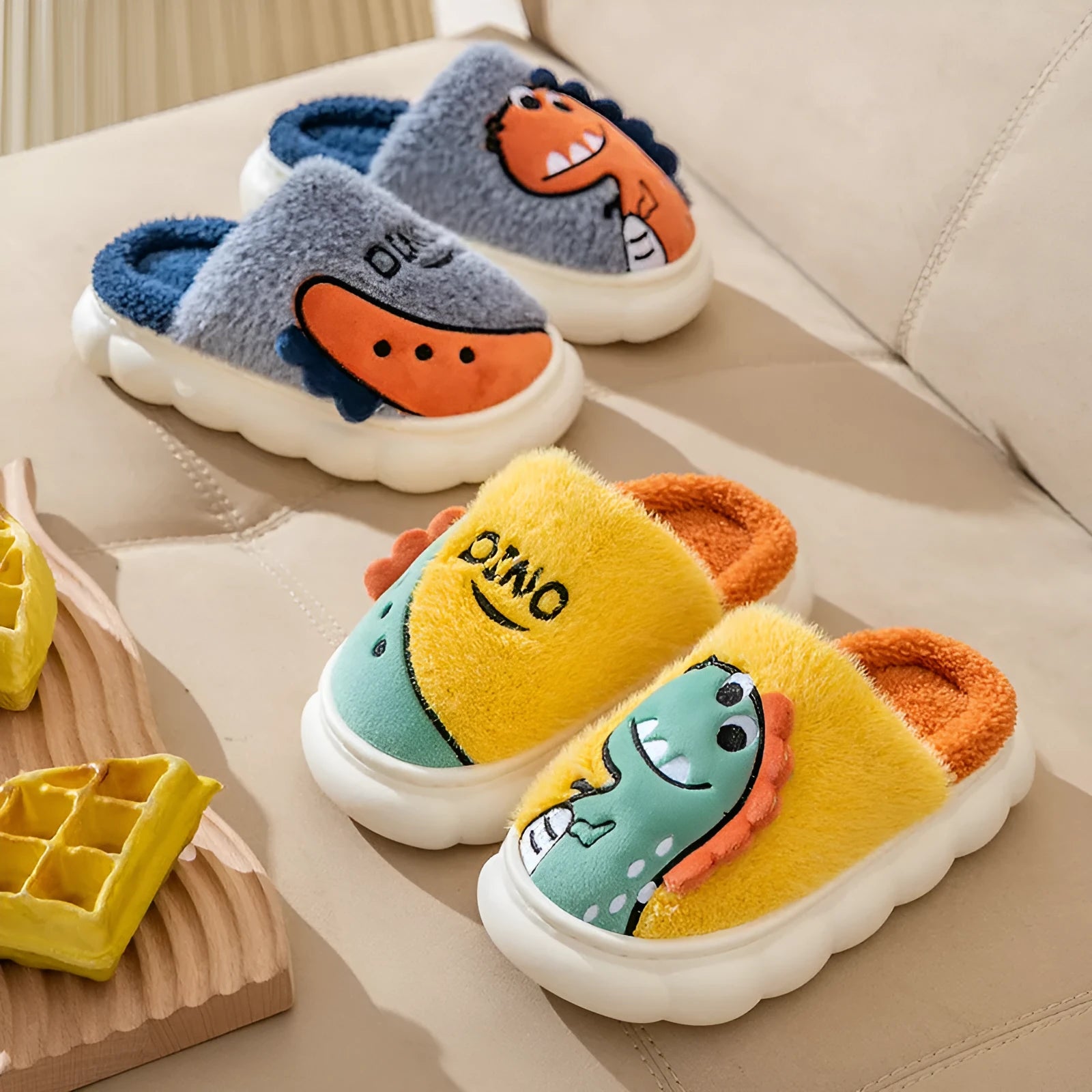 A pair of plush dinosaur-themed slippers for indoor wear, shown in a choice of colours.
