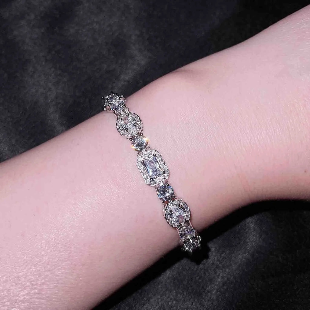 Women's geometric silver bracelet with inlaid white zircon stones on a wrist, showing adjustable clasp.
