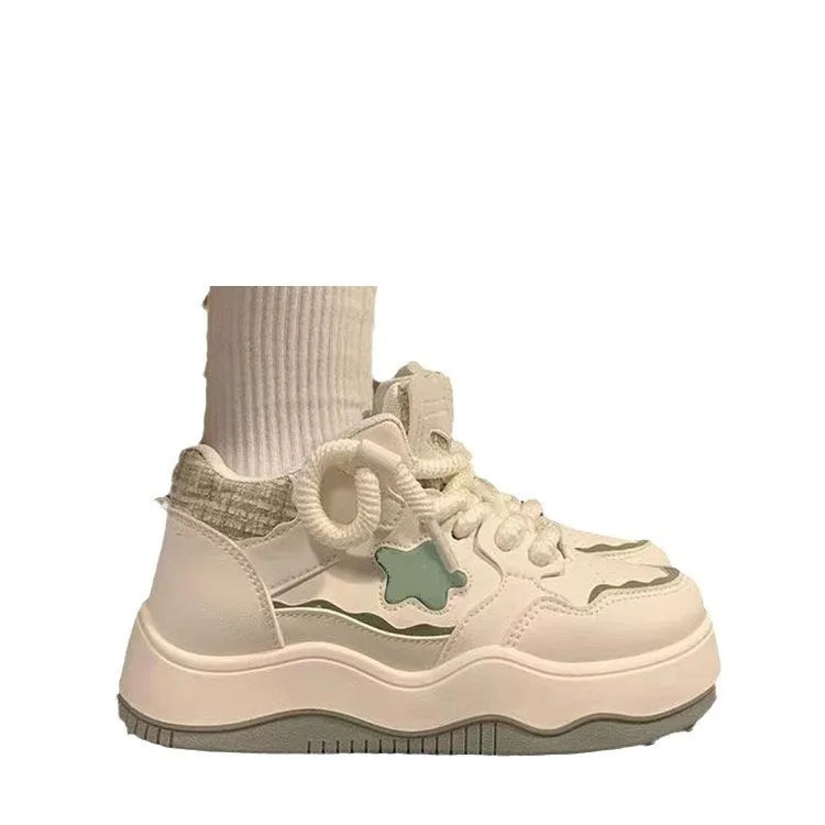 Women's green patent leather-look platform sneaker with round toe and white lace-up front, on a white background.