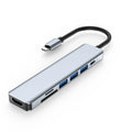 Silver 7-in-1 USB C hub docking station with HDMI, USB ports, and card readers on a desk.