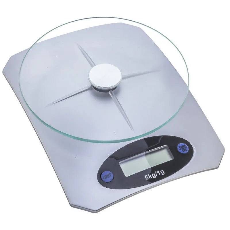 Simple mini kitchen electronic scale in silver white colour on a flat surface, showing weighing display.