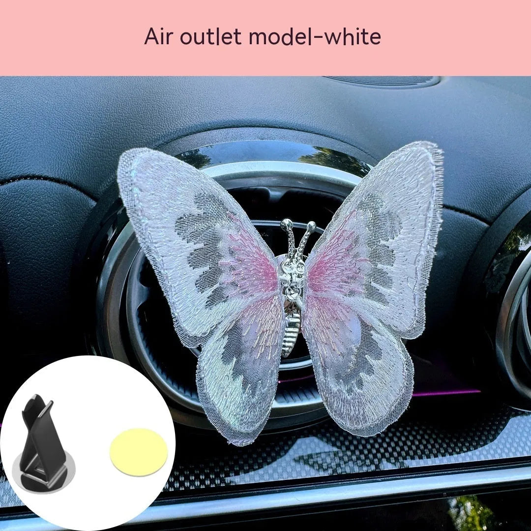 Soft fabric embroidered butterfly car air vent decoration in multiple colour options on a centre console.