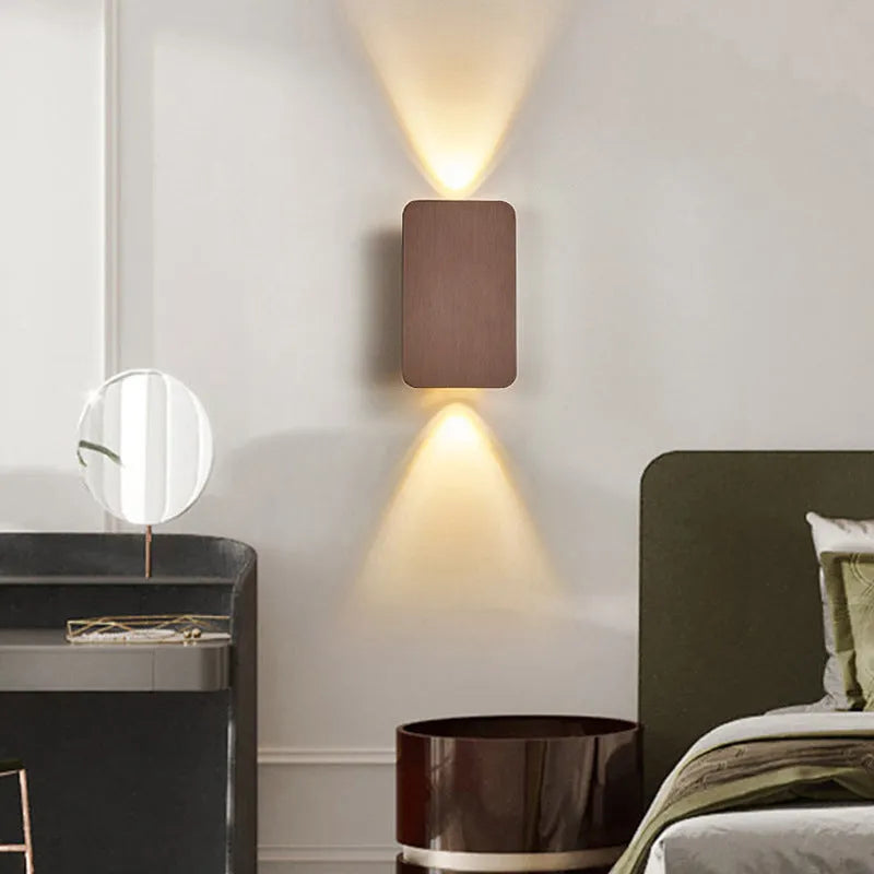 Minimalist black nordic wall lamp mounted beside a bed, emitting warm white light.