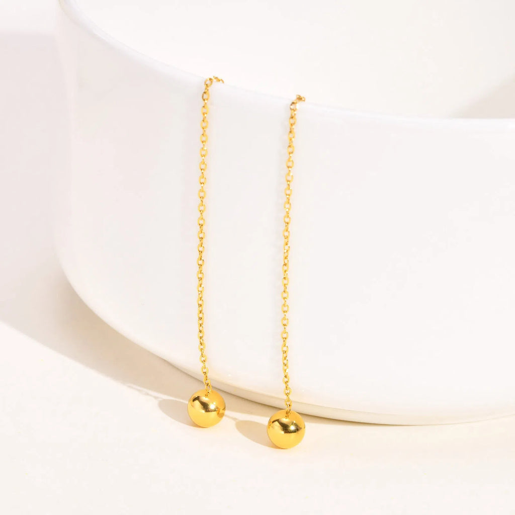 Gold-toned alloy drop earrings with round bead design on white background