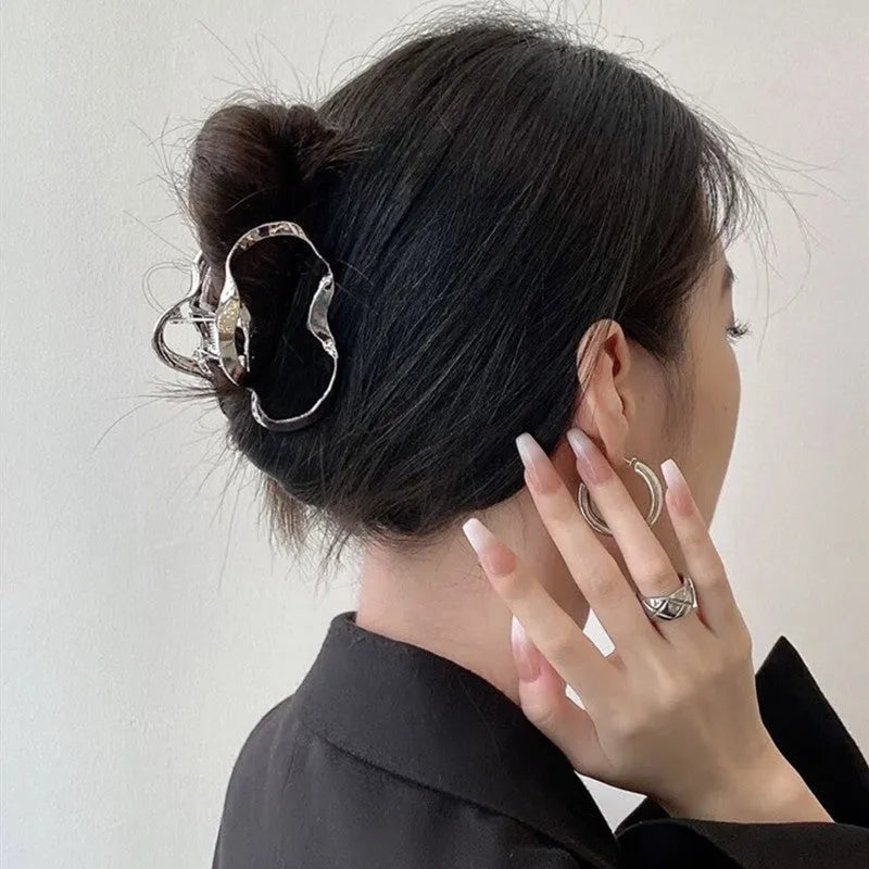 Silver metal hair claw barrette showing one of 45 designs, such as a bow or rose, on a white background.