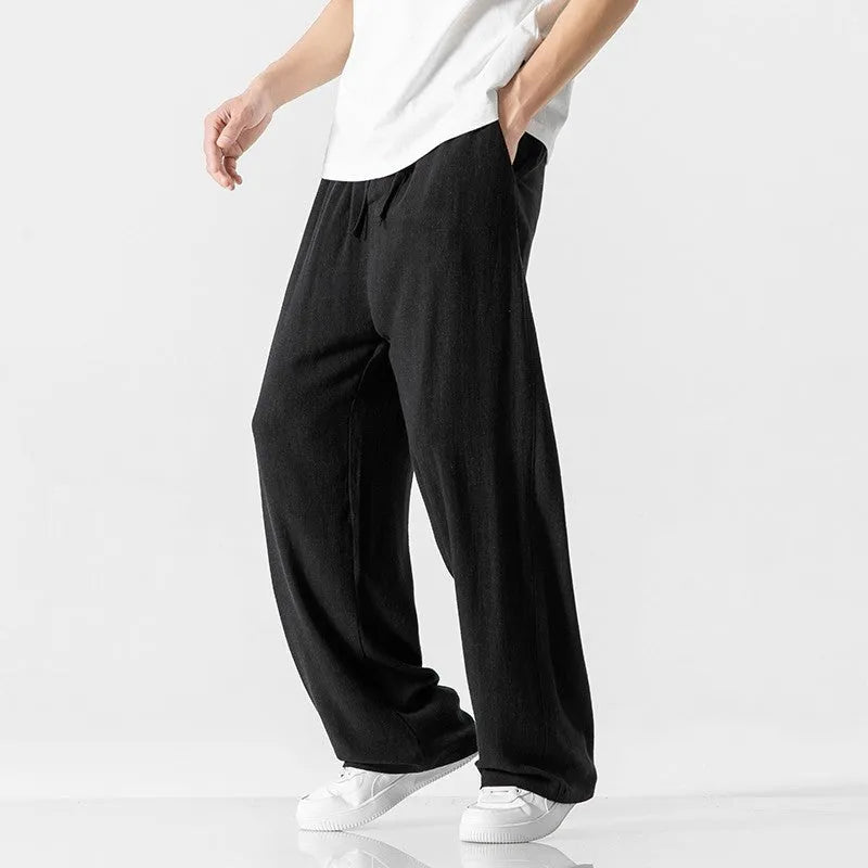 Man wearing beige cropped straight-leg bamboo fibre trousers with a drawstring waist on a summer day.