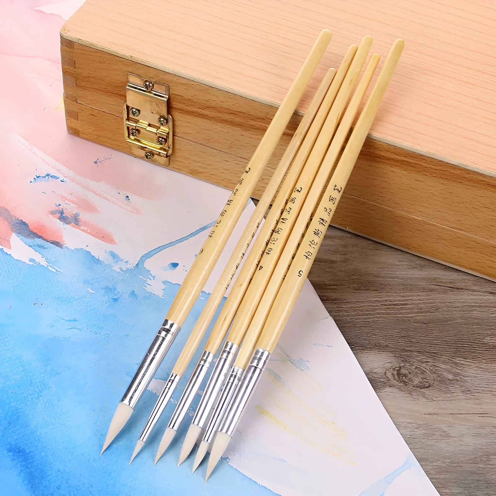 Set of six wooden-handled artist brushes with pointed synthetic wool bristles on a white background.