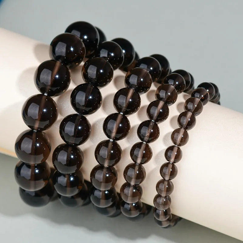 Hand-woven round obsidian crystal bracelet in black, silver, and rainbow eye colours on a neutral background.