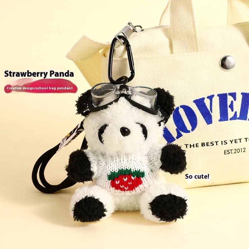 Cute plush strawberry bear doll keychain pendant on a soft surface, showing the cartoon bear with strawberry sweater design