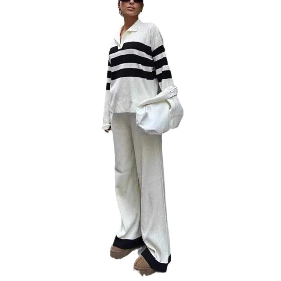 Women's black knitted polo shirt with white stripes and matching trousers laid flat.