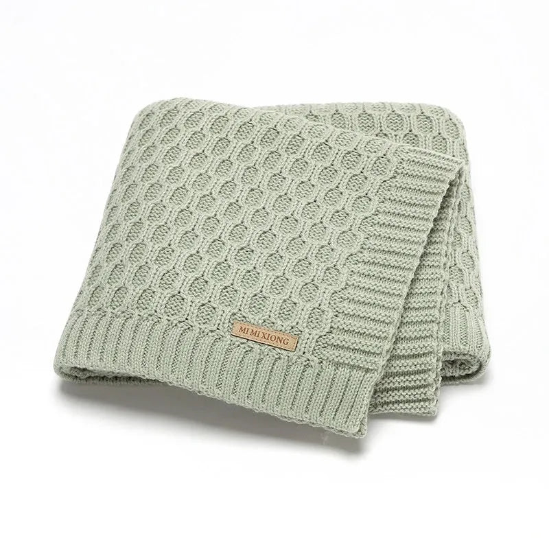 Solid colour baby blanket with textured three-dimensional lines, shown in beige khaki.