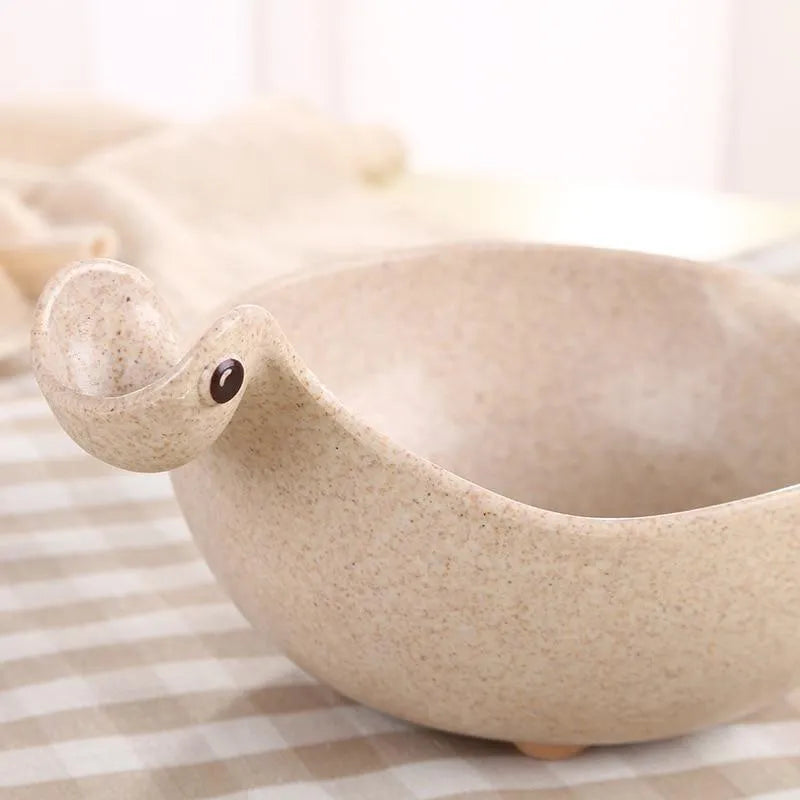 Cute tiny dinosaur bowl made of natural wheat straw fibre in pink, green, and beige colours, lightweight non-slip unbreakable design