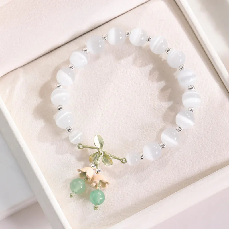 Close-up of a women's opal cat's eye stone beaded bracelet with diamond-shaped beads on a wrist.