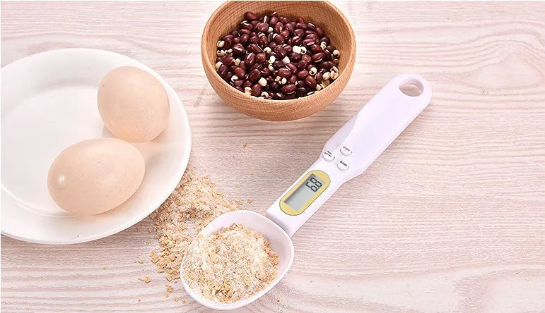 Black electronic measuring spoon scale on a kitchen counter showing digital display.
