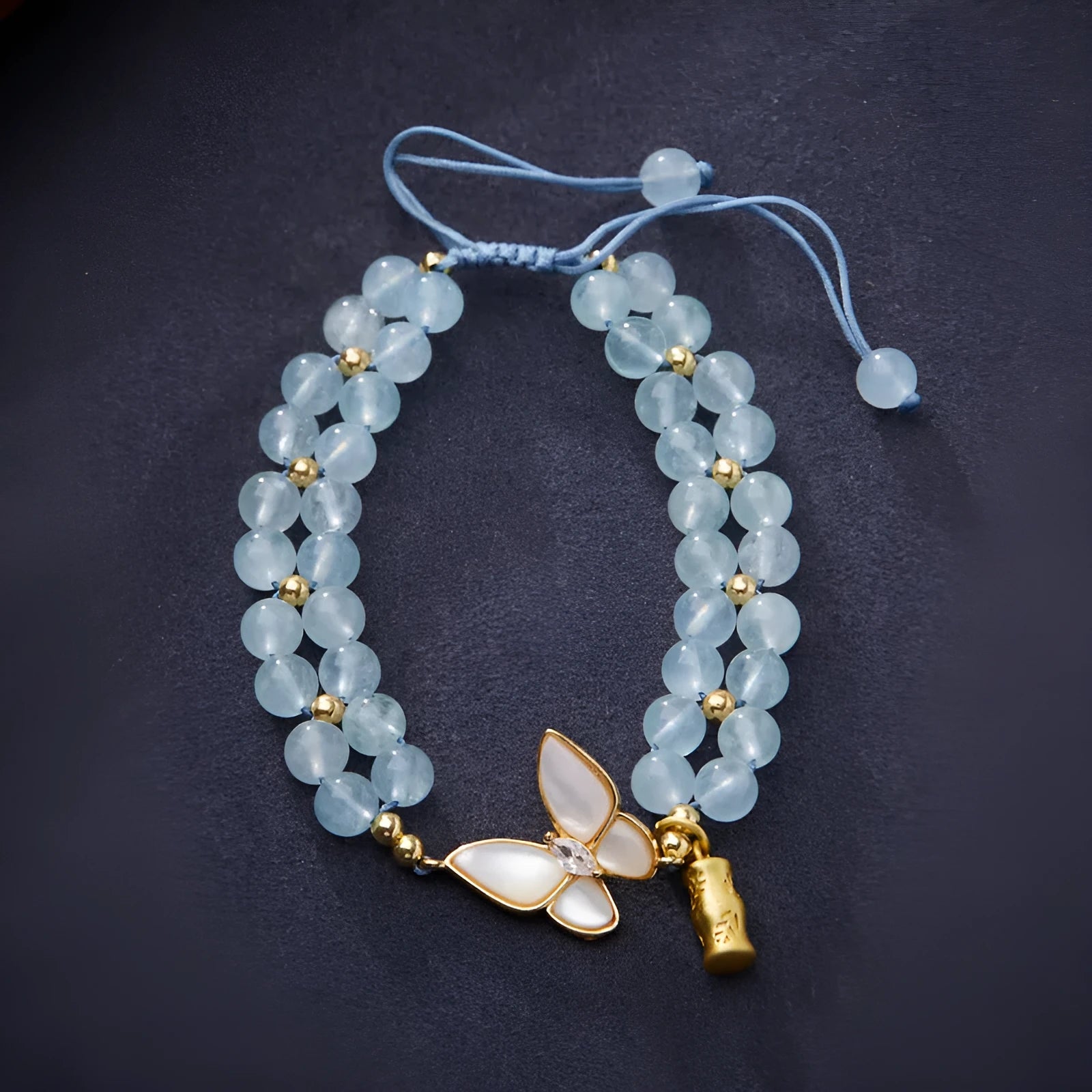 Close-up of a handmade women's woven bracelet with 6mm butterfly design in aquamarine gemstone beads.