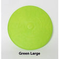 Plastic dog flying disc toy in green, shown on grass for scale