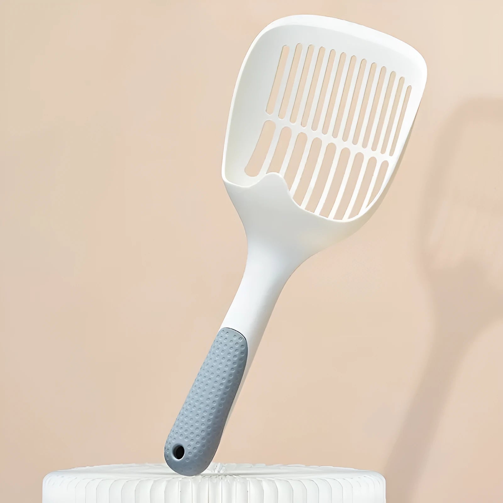 White plastic cat litter scoop with storage base for containing tool between uses