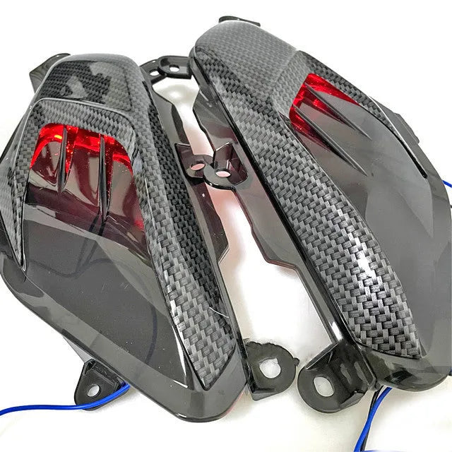 Pair of YAMAHA NMAX LED side lamps with carbon fibre trim, showing blue and red light options.