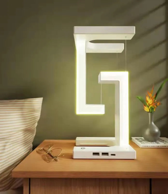 White magnetic suspension table lamp with wireless charging base, floating shade, and foldable bracket on a desk