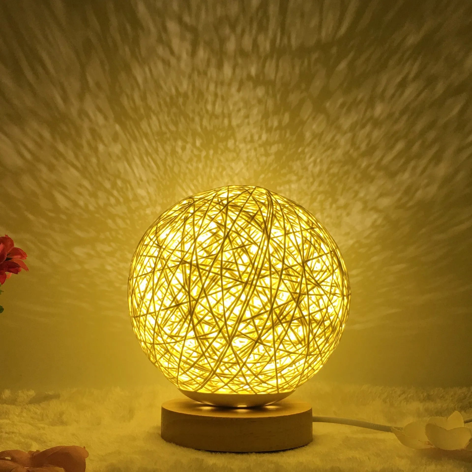 Rattan ball table lamp with woven shade and warm LED lighting on wooden surface