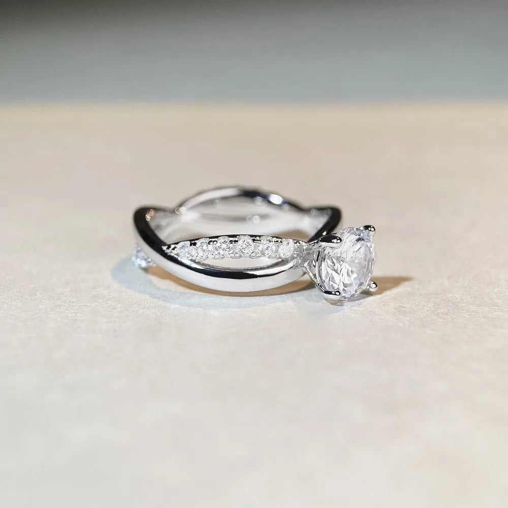 Silver ring with 1 karat moissanite in four-claw setting on a geometric twisted arm band.