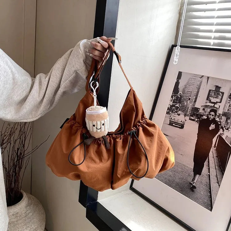 Soft foldable polyester crossbody bag in beige colour showing split pocket and crossbody strap.