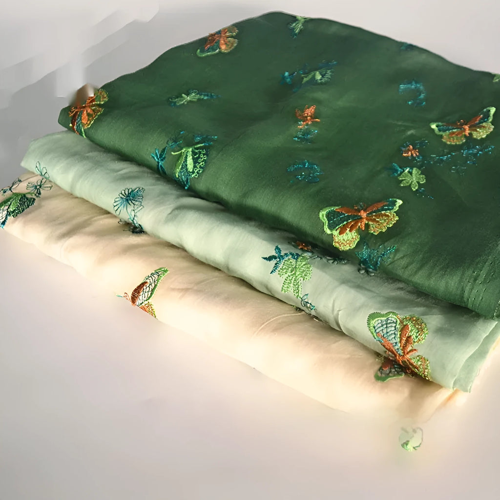 Close-up of textured 100% ramie fabric in beige, grass green, and dark green colours, showing its width.