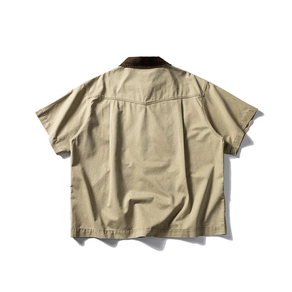 A khaki washed cotton overalls shirt with short sleeves and a loose cardigan style, laid flat.