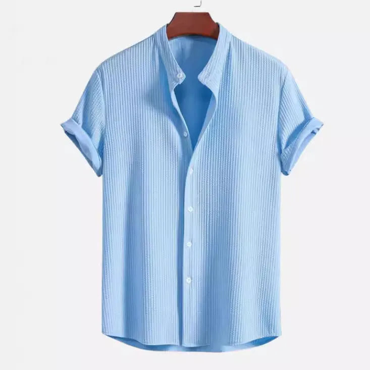 A man wearing a loose-fitting short sleeve casual shirt in a solid colour.