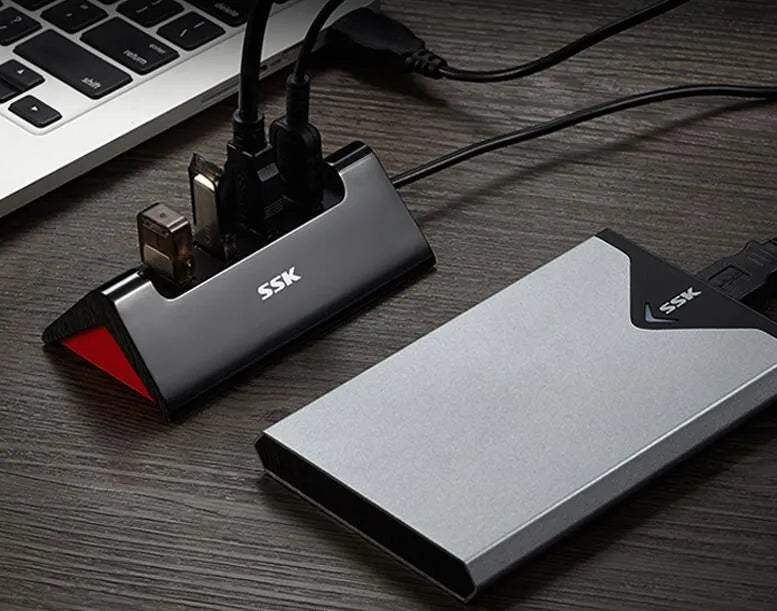 Black plastic USB hub with four USB-A ports and a Micro USB power port on a desk.