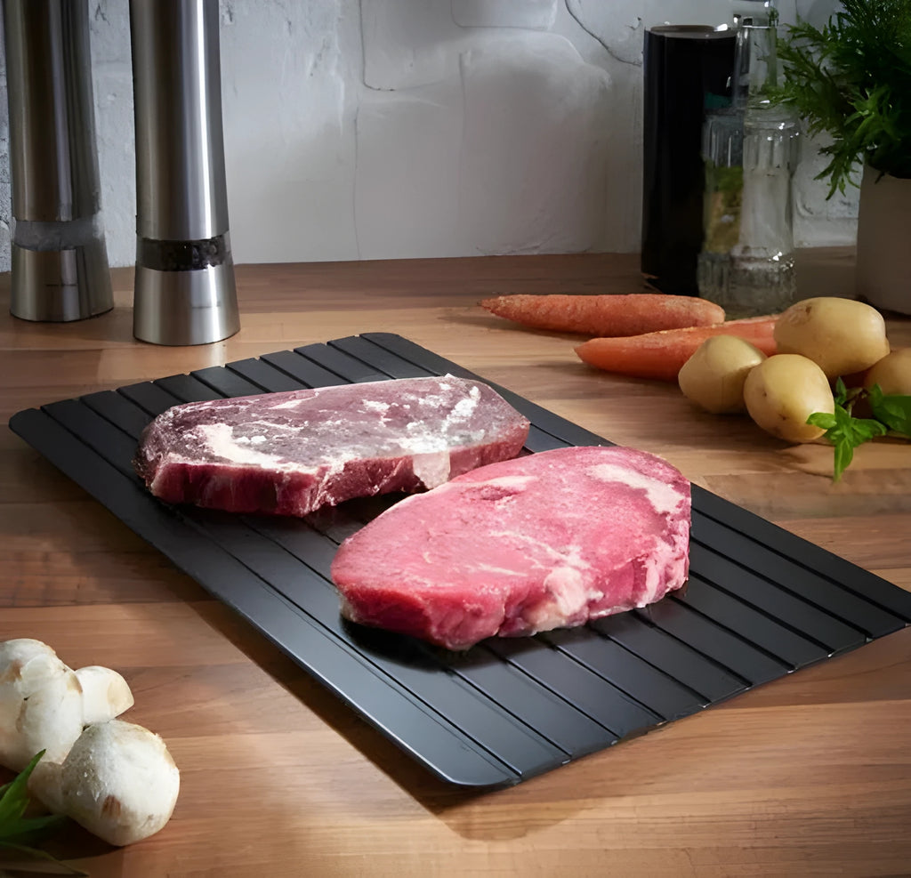 Black aluminium fast defrosting tray with silica gel feet on a kitchen countertop.