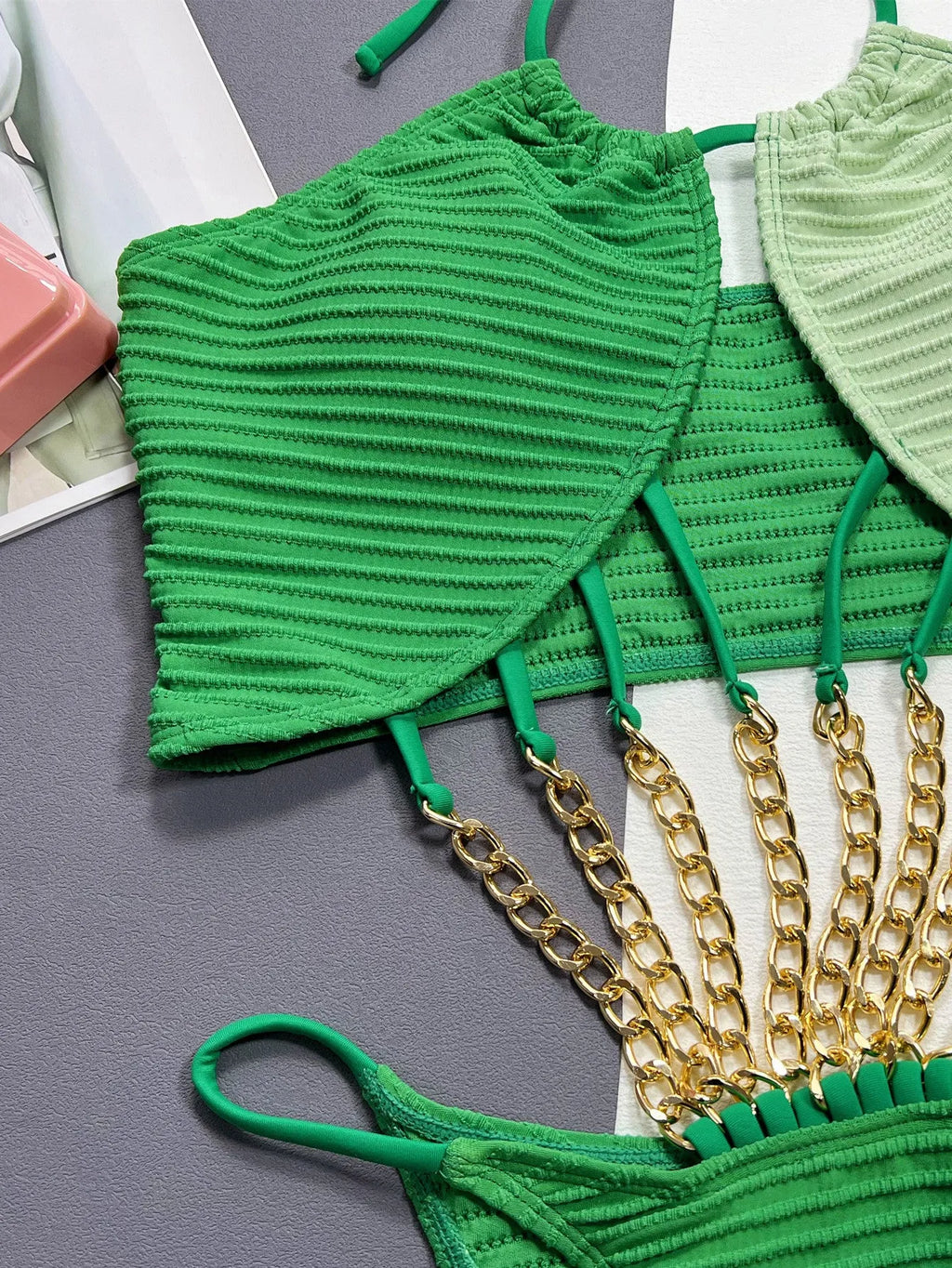Solid green women's one-piece swimsuit on a hanger, showing hollow design.