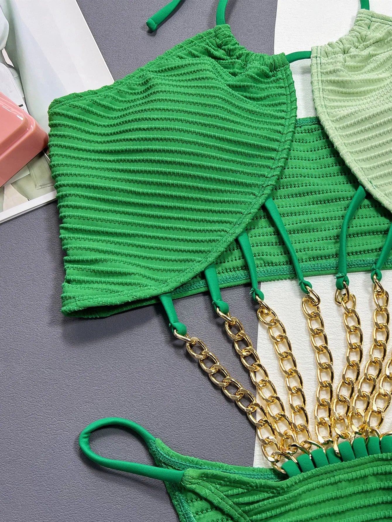 Solid green women's one-piece swimsuit on a hanger, showing hollow design.