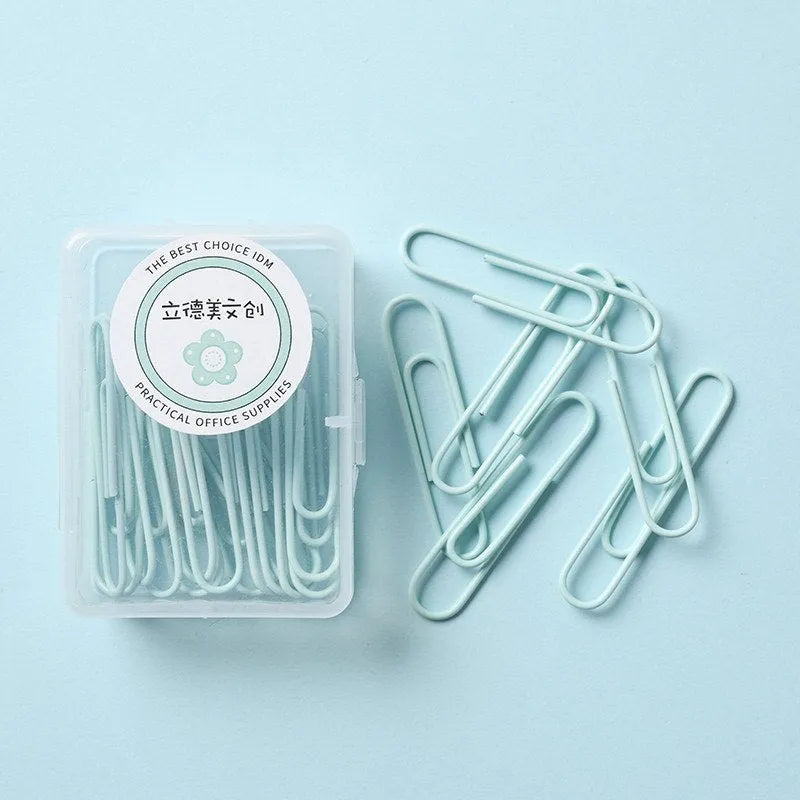 Macaron-color paper clips in pastel shades including pink, green, and purple on a white desk