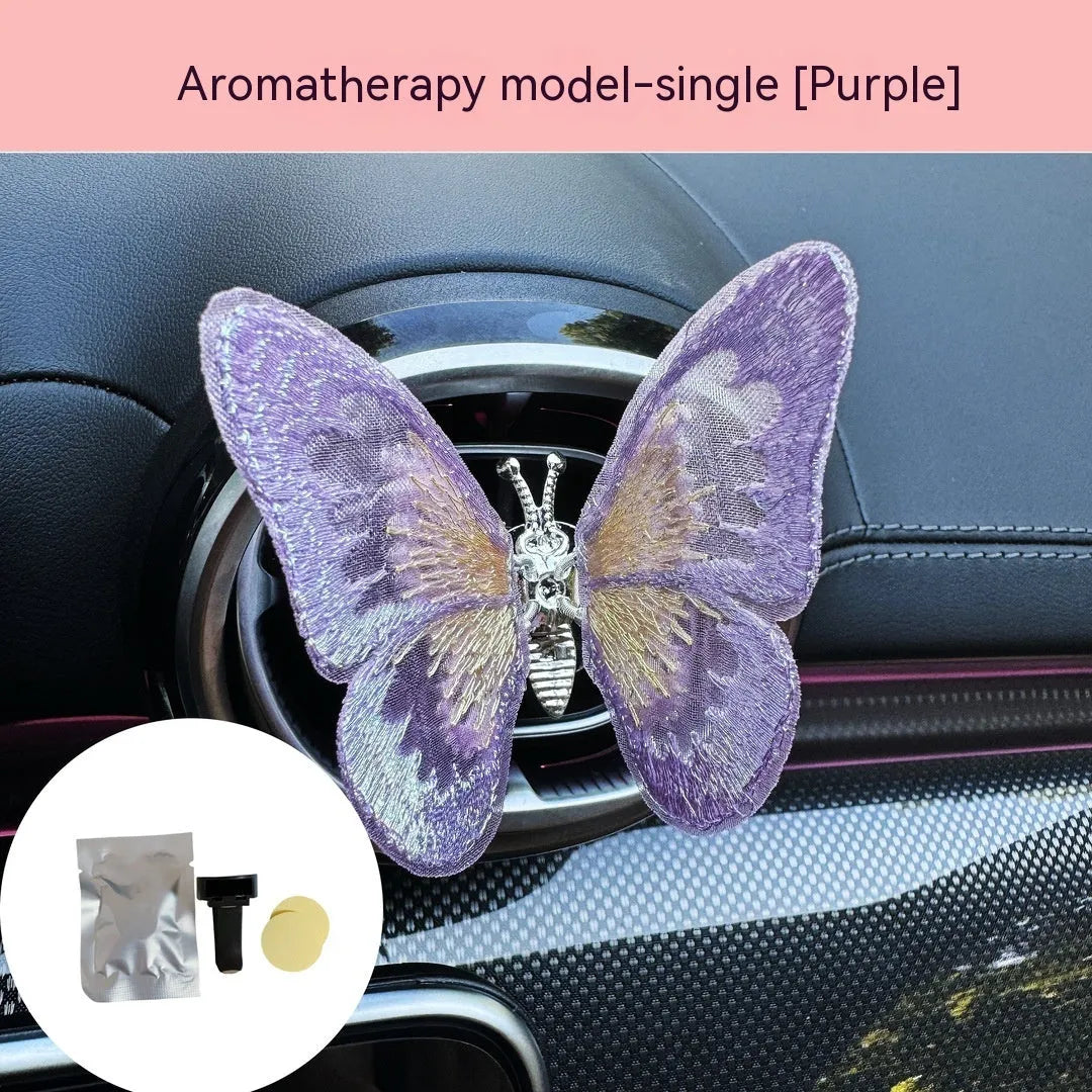 Soft fabric embroidered butterfly car air vent decoration in multiple colour options on a centre console.