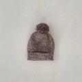 Dark brown knitted three-piece set for infant girl with fur ball hat, blouse, and shorts.